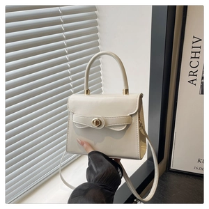 Dettaglio della borsa in pelle color crema con chiusura dorata e ombra elegante