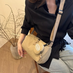Détail d'un sac bandoulière en nylon kaki avec petite pochette ronde amovible et sangle