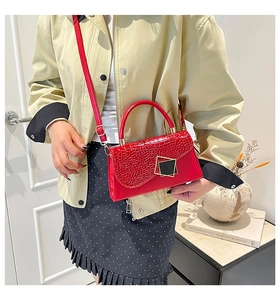 Detail view of red crocodile pattern flap bag with gold hardware and leather strap