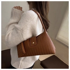 Close-up of caramel woven pattern underarm bag with gold buckle on white sweater