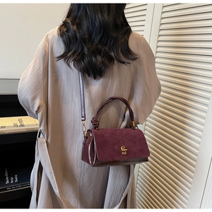 Detail of burgundy patchwork crossbody bag showing suede flap and glossy patent finish