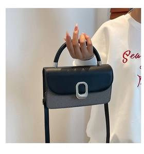 Détail du sac à main bicolore montrant le tissu texturé et la boucle en métal argenté