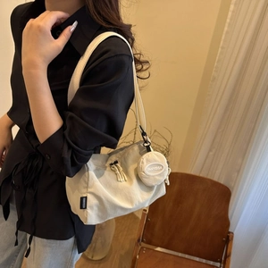 Détail d'un sac demi-lune en nylon blanc cassé avec double fermeture et petite pochette ronde