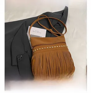 Détail du sac à bandoulière marron avec clous dorés et longues franges bohèmes