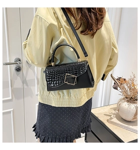 Detail of crocodile embossed crossbody bag with golden square buckle and adjustable strap