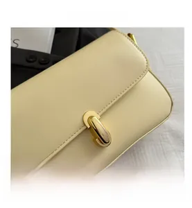 Close-up of smooth pale yellow leather texture and polished oval gold metal buckle