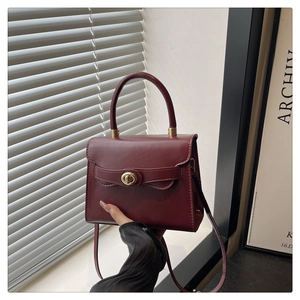 Dettaglio borsa bordeaux in pelle PU con chiusura a rotazione dorata e manico arrotondato