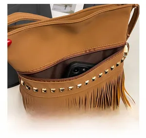 Détail de la poche avant zippée du sac à bandoulière marron avec franges et clous