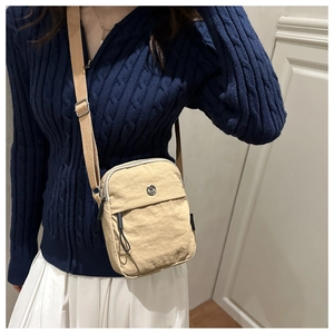 Detail of adjustable strap and zipper pockets on a nylon crossbody bag for daily styling