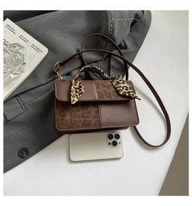 Detailed view of brown leather crossbody bag with leopard print texture and silk scarf handle