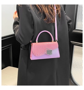 Detail view of pink croc-embossed flap handbag with silver buckle and black blazer contrast