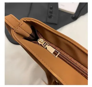 Détails de la fermeture éclair dorée et des coutures sur le sac seau en cuir marron