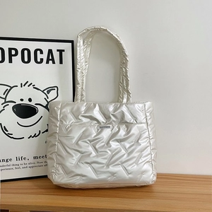 Sac cabas matelassé argent métallisé avec texture cousue sur fond de bois clair
