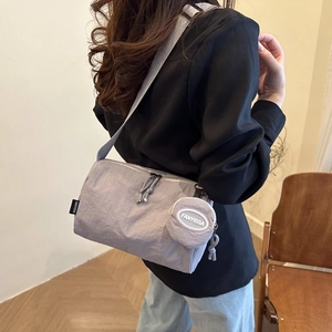 Gros plan du sac bandoulière en nylon gris clair avec sangle et petit porte-monnaie