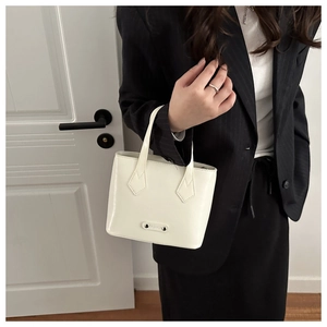 Detail of a minimalist cream white handbag with polished leather and fashion logo plaque