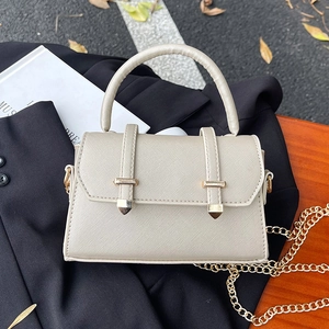 Sac bandoulière beige chic avec chaîne dorée et fermoir sur un fond élégant et moderne