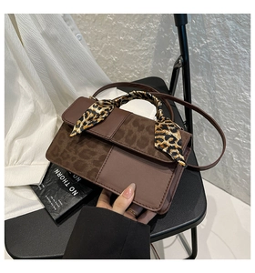 Detail of a brown patchwork handbag with leopard print scarf and slim shoulder strap
