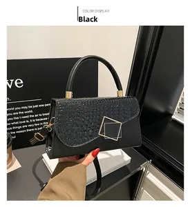Detail of black crossbody bag featuring crocodile texture flap and gold square buckle