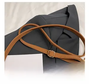 Détail d'une bandoulière en cuir marron réglable avec boucle en métal doré poli
