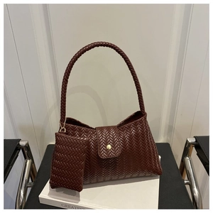 Detailed view of dark brown woven underarm bag with gold metal buckle and matching pouch
