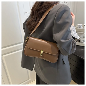Detail of brown leather baguette bag with a vintage gold buckle worn by a model