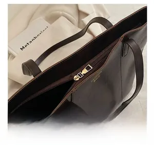 Close-up of smooth gold zipper and embossed logo on vintage brown faux leather tote bag