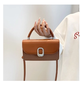 Gros plan du sac bandoulière en cuir caramel avec boucle en métal argenté et surpiqûres