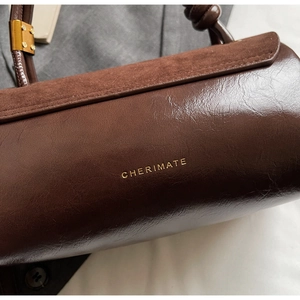 Detail shot of brown leather and suede texture contrast on a minimalist handbag