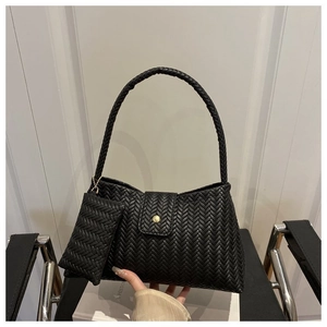 Close-up of black woven leather shoulder bag featuring gold buckle and mini pouch detail