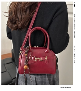 Close-up of wine red leather handbag with gold horsebit detail and elegant rope charm