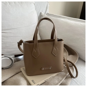 Close-up of caramel brown leather bucket bag on a magazine with headphones