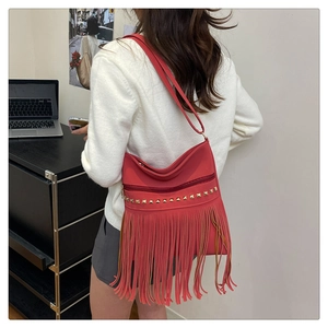 Close-up of bright red bucket bag with long bohemian tassels and golden studs