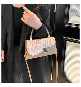 Detail of a dual-textured crossbody bag with faux crocodile flap and metal clasp