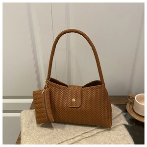 Detailed view of brown woven texture shoulder bag with gold clasp on soft fabric