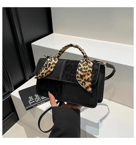 Detail of black crossbody bag featuring leopard print texture and decorative silk scarf handle