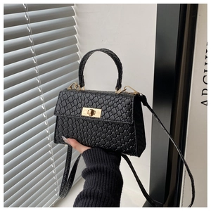 Détail d'un sac à main noir motif crocodile avec fermoir doré et bandoulière fine