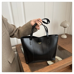 Détail du grand sac cabas noir en cuir avec lettrage doré et texture grainée souple