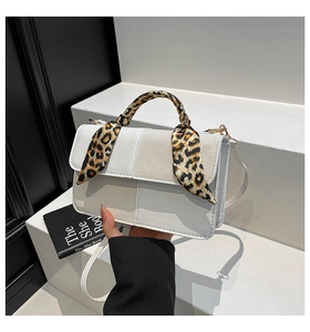 Detail of white leather box bag with leopard print silk scarf wrapped on the handle