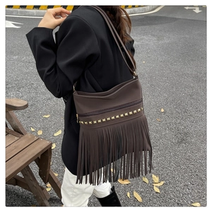 Detail of brown faux leather shoulder bag featuring long fringe and gold square rivets