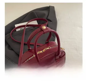 Detail view of burgundy leather doctor bag with gold zipper and round handles