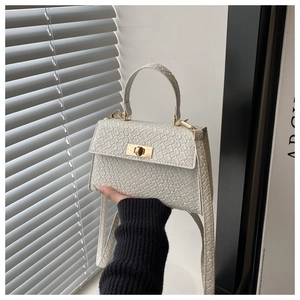 Gros plan du sac à main crème à motif crocodile avec fermoir rotatif doré élégant