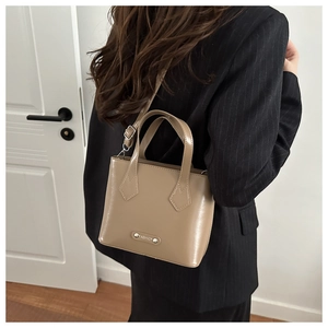 Detailed view of khaki leather bucket bag texture and silver FASHION metal plate detail