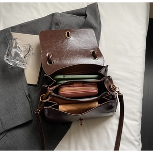 Deep brown faux leather crossbody bag with three internal compartments and metal clasp