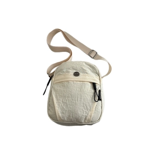 Minimalist cream nylon crossbody bag with adjustable strap and metallic logo detail