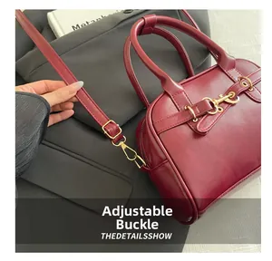 Detail of adjustable strap buckle on vintage wine red leather bag with gold hardware