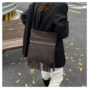 Detail of dark brown vintage tassel crossbody bag with gold studs and matte leather finish