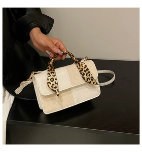 Detail of minimalist cream-beige square handbag with leopard print scarf handle wrap