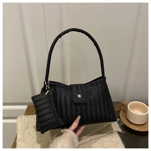 Detail of black woven leather shoulder bag with matching mini pouch on a desk