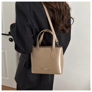 Detail of taupe leather bucket bag with metal 'FASHION' tag and adjustable strap