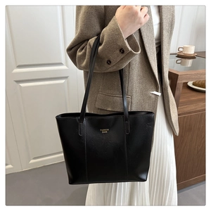 Détail du grand sac cabas noir avec lettrage doré et texture en cuir synthétique